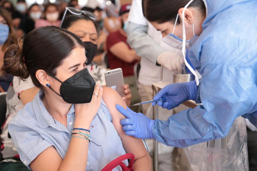 Una enfermera aplica una dosis de la vacuna a una mujer joven